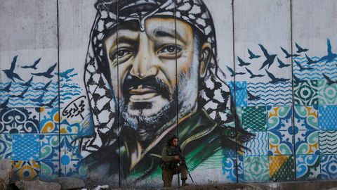 Un soldado israel de guardia frente a un mural que representa al lder palestino Yasser Arafat, fallecido durante enfrentamientos con manifestantes palestinos cerca del puesto de control de Qalandiya