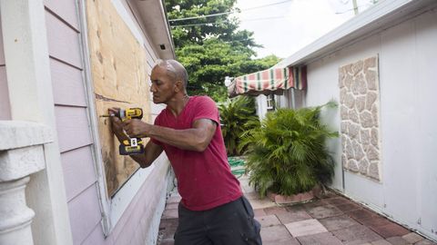Un hombre tapa las ventanas de su hogar con tablones contrachapados.