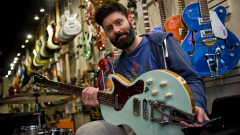 Fran Borrego, dueño de la tienda Rockbox de A Coruña, con decenas de guitarras eléctricas a sus espaldas  