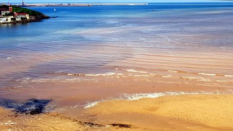 Vista area de la playa de San Lorenzo con la mancha y las espumas
