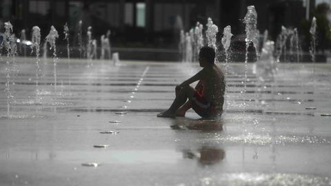 Un hombre se refresca en una fuente de Córdoba debido a las altas temperaturas que se han alcanzado hoy con la llegada de la primera ola de calor del verano