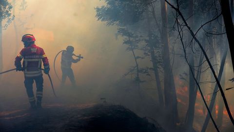 Varios bomberos luchan contra las llamas en un incendio forestal declarado en Belem, cerca de Monchique, en el Algarve portugués hoy, 8 de agosto de 2018. El primer ministro de Portugal, António Costa, descarta que el incendio desatado el pasado viernes en la sureña región del Algarve vaya a ser extinguido en las «próximas horas», y auguró que serán necesarios «días» para controlarlo.