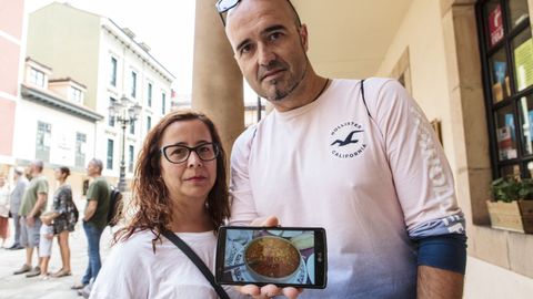Turistas que pasean por Oviedo muestran una foto de uno de los platos que ms han disfrutado durante sus vacaciones por Asturias: los callos