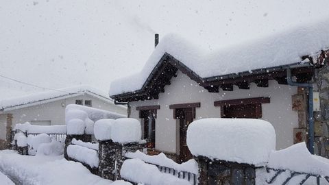 Las casas del pueblo de Pajares con los tejados y las verjas cubiertas de nieve