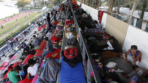 Un grupo de migrantes descansan en las gradas de un estadio de Mxico