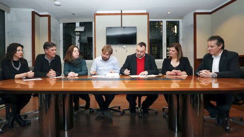 Los secretarios generales de los socialistas asturianos, Adrián Barbón (3d), y de Podemos Asturies, Daniel Ripa (4i), junto a responsables de los dos partidos, durante la firma de un acuerdo presupuestario para 2019.