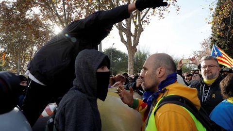 Un manifestante independentista trata de impedir que un grupo de encapuchados vuelquen contenedores en las inmediaciones de la Llotja de Mar de Barcelona