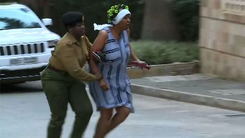Una mujer huye del lugar donde se produjo la explosión acompañada de un miembro de las fuerzas de seguridad