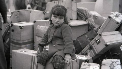 Unha nena agarda pola sa nai sentada nas maletas na Corua de 1963, nunha das instantneas da exposicin Os adeuses que viaxar a Estados Unidos