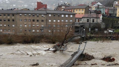 Aspecto que presenta una pasarela peatonal sobre el río Aller a causa del temporal de lluvias registrado en los últimos días en Asturias