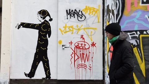 Un hombre camina frente a una pintura que muestra a la primera ministra británica, Theresa May, sonámbula con un pijama negro cubierto de estrellas amarillas similares a las de la bandera de la Unión Europea