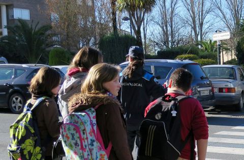 Alumnos cruzan un paso de peatones, en mitad de coches aparcados, en las inmediaciones de un colegio