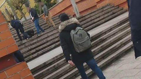 El Policía se agacha junto al herido, ante la mirada de las otras dos personas que le acompañan