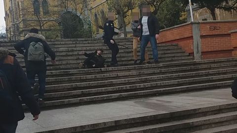 El Policía se gira con el tolete, dejando detrás al herido. A su lado las otras dos personas que han estado a su lado. Uno sujeta del brazo al otro