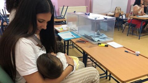 La presidenta de una mesa electoral de Arahal (Sevilla) amamanta a su hijo durante la votación
