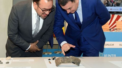 El rector de la USC, Antonio López —izquierda— y el conselleiro de Cultura, Román Rodríguez, observan los restos de la vasija prehistórica encontrada en el yacimiento arqueológico de Triacastela