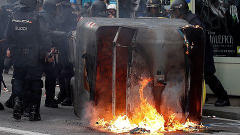 Agentes antidisturbios junto a un contenedor en llamas en Via Laietana