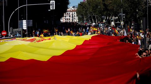 Decenas de personas sostienen la bandera de Espaa de 1.000 metros cuadrados unos 130 kilos de peso, durante la concentracin convocada por Vox 