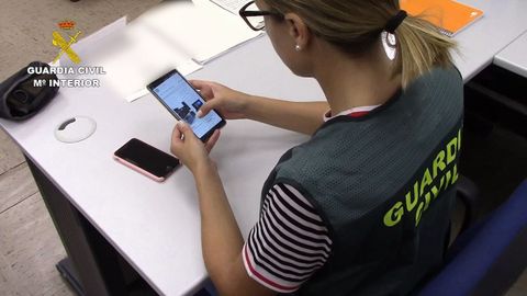 Una agente de la Guardia Civil investiga una estafa cibernética cometida a través de un móvil.