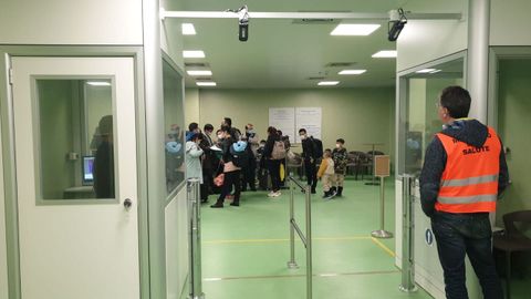 Los pasajeros que llegan al aeropuerto Fiumicino de Roma desde Wuhan en China esperan que el personal médico los revise en busca de signos de coronavirus