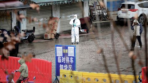 Un trabajador con traje de protección en el mercado cerrado de mariscos en Wuhan, provincia de Hubei, China