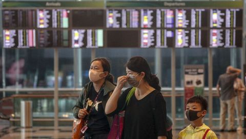 Una madre y sus hijos son vistos usando máscaras mientras caminan por el aeropuerto de Changi en Singapur