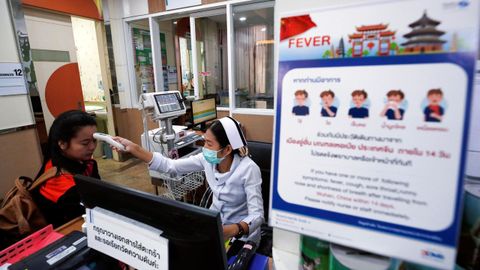 na enfermera mide la temperatura de una paciente al lado de un cartel que alerta del coronavirus, este miércoles en un hospital del Bangkok (Tailandia).