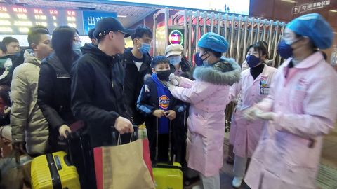 El personal médico verifica la temperatura corporal de los pasajeros cuando llegan a una estación de ferrocarril en la ciudad de Yingtan, provincia de Jiangxi, China