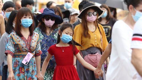 Turistas extranjeros se tapan con máscaras contra el coronavirus durante una visita al templo del Buda Esmeralda, en la ciudad tailandesa de Bangkok