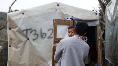 Un hombre sostiene a su hijo en un campamento improvisado aledaño al campo de Moria