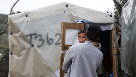 Un hombre sostiene a su hijo  en un campamento improvisado aledao al campo de Moria