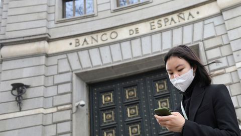 Una mujer con mascarilla frente al Banco de España en Madrid