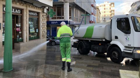 Personal de limpieza de Urbaser en Ferrol baldeando delante de la farmacia del Callao por el coronavirus