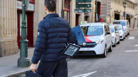 Un trabajador portando su ordenador para teletrabajar, en una calle de Vigo