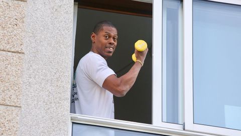 Una persona confinada en casa por el coronavirus aprovecha su ventana para hacer ejercicio físico con unas pesas
