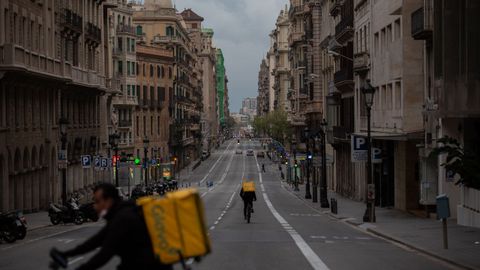 Dos trabajadores en bicicleta por una calle de Barcelona