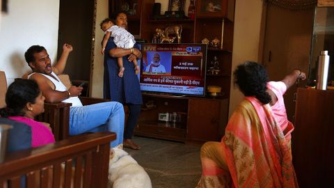 Una familia escucha el discurso televisado del primer ministro indio Narendra Modi en Bangalore, India
