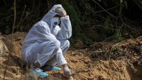Un familiar se despide de una víctima del coronavirus ante una fosa común en Nueva Delhi, La India