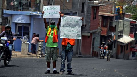 Dos hombres piden dinero y comida mientras sostienen carteles en los que informan su situación de pobreza en Tegucigalpa, Honduras