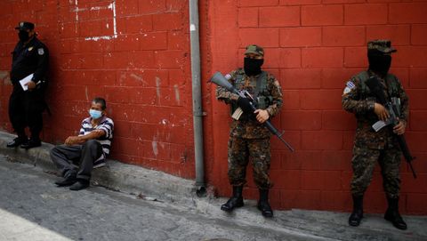 Varios policías custodian a un dentido acusado de violar la cuarentena en San Salvador, El Salvador