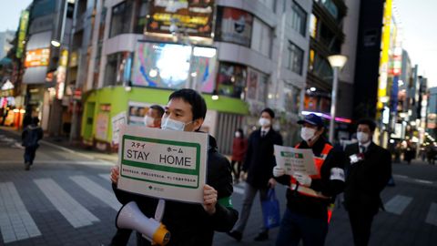 Funcionarios del gobierno metropolitano de Tokio pasean con carteles en los que animan a la población a quedarse en casa