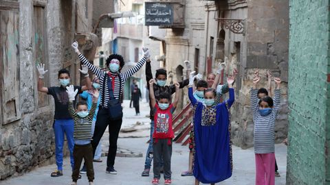 El clown egipcio Ahmed Naser divierte a unos niños, que se protegen con mascarillas, en El Cairo, Egipto