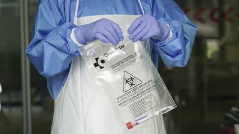 Un sanitario sostiene una bolsa con una muestra para realizar un análisis PCR