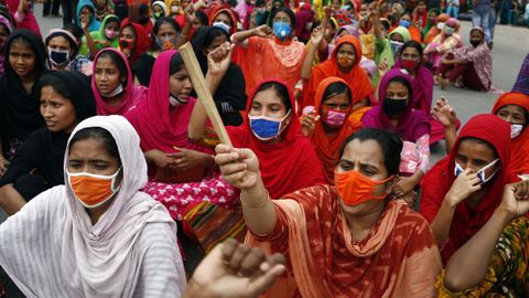 Trabajadoras de la confección de Bangladesh, algunas con máscaras protectoras, gritan consignas y bloquean una carretera durante una protesta para exigir el pago de salarios en Dhaka. Miles de trabajadoras del sector no fueron pagadas por las fábricas después de que se cancelaran exportaciones por valor de alrededor de tres mil millones de dólares debido a la pandemia causada por el coronavirus