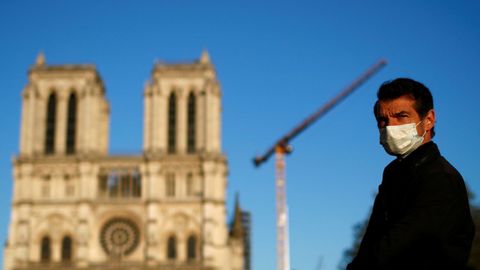 Un hombre con mascarilla escucha la gran campana de la catedral de Notre-Dame de París, que sonó de forma simbólica como señal de la resistencia del edificio un año después del devastador incendio que afectó al monumento