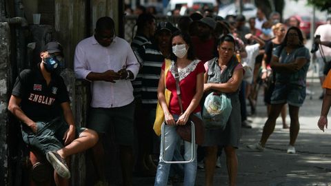 Habitantes de Río de Janeiro (Brasil) esperan en la fila a las puertas de un banco público, donde la mayoría de ellos acuden para recibir la ayuda de emergencia otorgada por el gobierno federal a los más vulnerables durante el brote de COVID-19