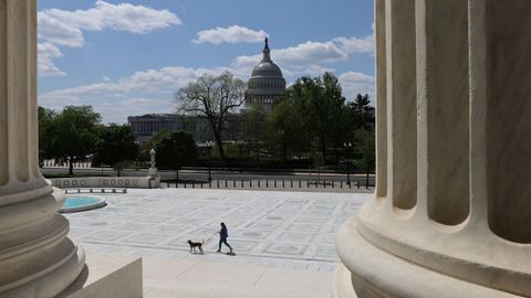 Una mujer pasea a su perro en la explanada del Tribunal Supremo con el Capitolio al fondo