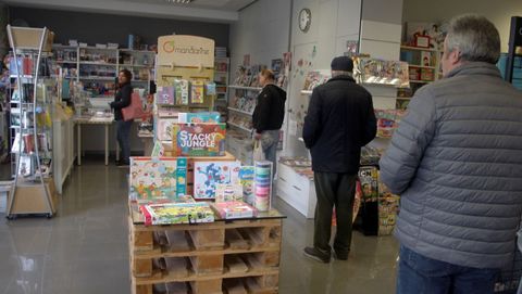 Un grupo de personas esperan a ser atendidas en una librera de Gijn