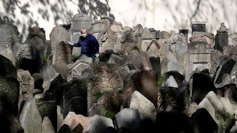Un operario del cementerio judío de Praga, trabajando con mascarilla