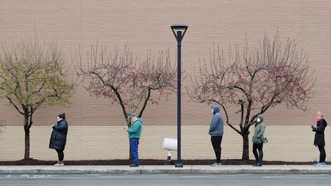 Las personas respetan el distanciamiento social en el acceso a una tienda en Massachusetts